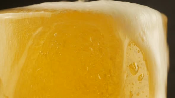 Close up background of pouring beer with bubbles and foam in glass alt
