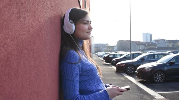 Beautiful young woman listening music with headphones and smart phone outdoor alt