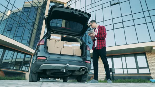 A Guy Delivers Boxes, Taking Them From Trunk. alt