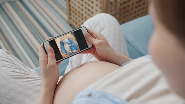 Pregnant Woman Watching Video of Baby in Womb Using Smartphone Enjoying Pregnancy