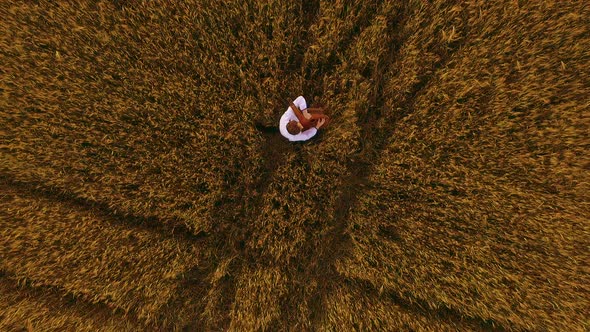 Aerial Shot of Banduryst Ukrainian Musician Kobzar Playing in Grainfield Sitting in Wheat Field with