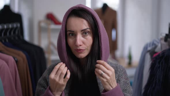 Front View Closeup Smiling Woman Putting on Hood of Hoodie in Slow Motion Looking at Camera alt