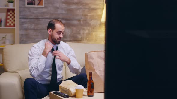 Caucasian Businessman Untying His Tie Sitting on Couch alt