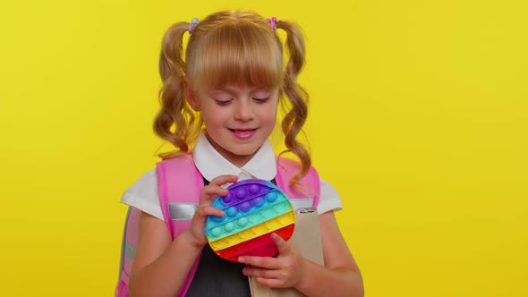 Funny Pupil Girl Playing with Pop It Sensory Antistress Toy Kid Presses on Colorful Squishy Bubbles alt