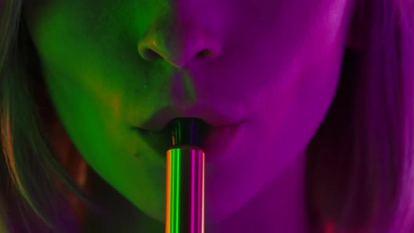 Portrait of a Young Stylish Woman Smokes Hookah and Blows White Smoke Directly Into the Camera alt