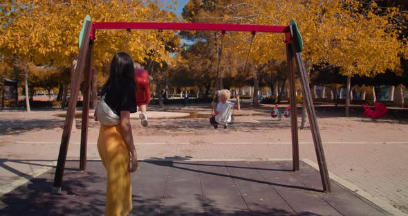Camera Move Through Fly Swing with Little Swinging Children on Autumn Sunny Day