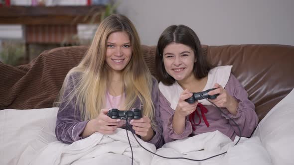 Front View Two Positive Young Women Playing Video Game with Joysticks Smiling Looking at Camera alt