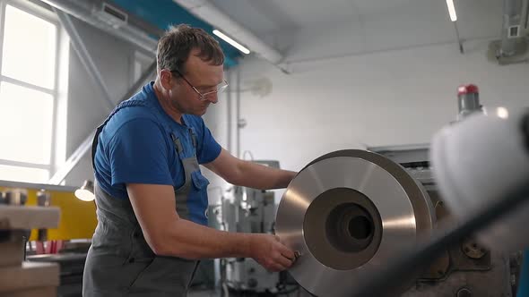 The Turner Processes the Metal Part on a Lathe in a Lathe Shop