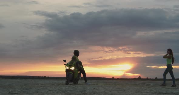 Couple Embracing Near Motorbike on Beach at Sunset