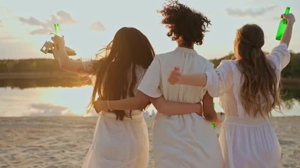 A Group of Female Friends Running in an Embrace on a Lake Beach at Sunset