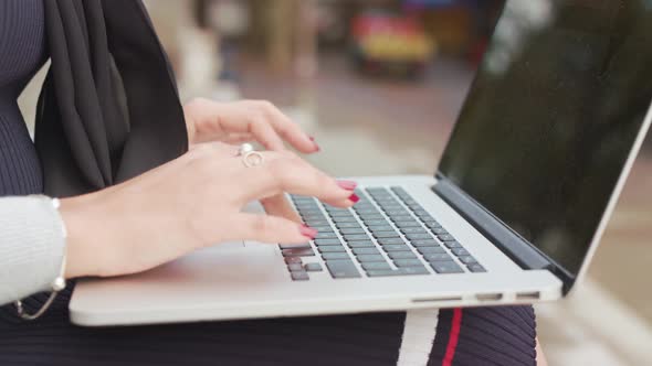 Close Up Shot Of Woman Sat Outside Typing/Working On Her Laptop As People Walk Past alt