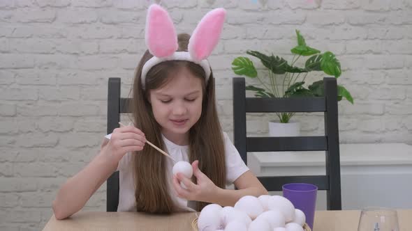 Little Girl Wearing Bunny Rabbit Ears Painting Eggs for Easter alt