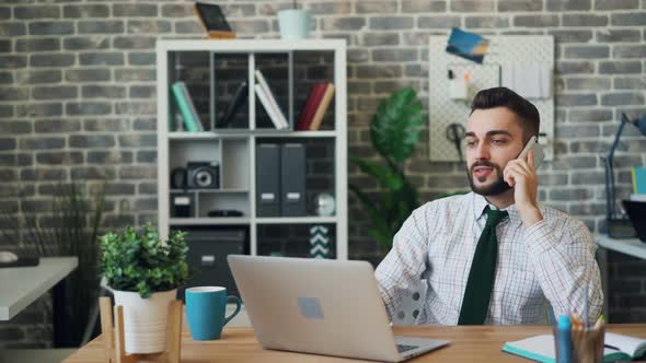 Office Worker Talking on Mobile Phone and Using Laptop Working Alone alt