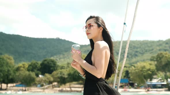 Asian sexy black dress girl with bikini drink a glass of wine and look relax on yacht boat ship alt