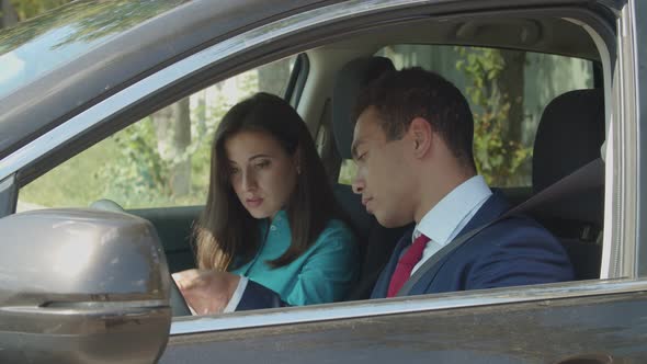 Mixed Race Businesspeople in Car Analyze Documents alt