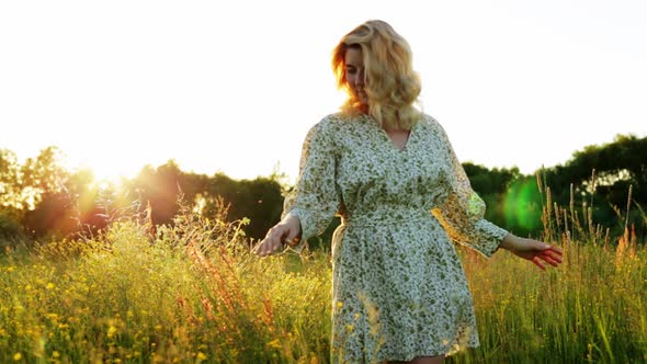A Woman is Walking Along a Green Meadow