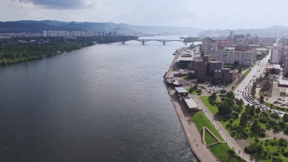 Fly Over a Wide River on a Drone Overlooking the City alt