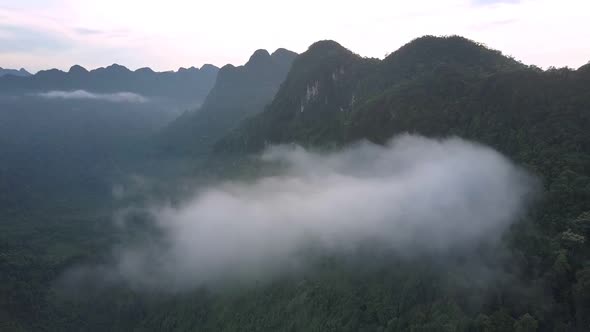 Gray Fog and Little Clouds Hang Among High Mountain Range alt