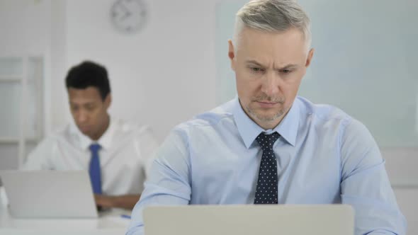 Pensive Grey Hair Businessman Thinking and Working on Laptop alt