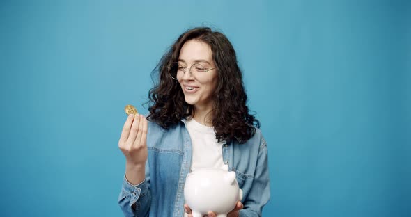 A Happy Young Girl Holds a Bitcoin in a Treasure Trove of Money alt