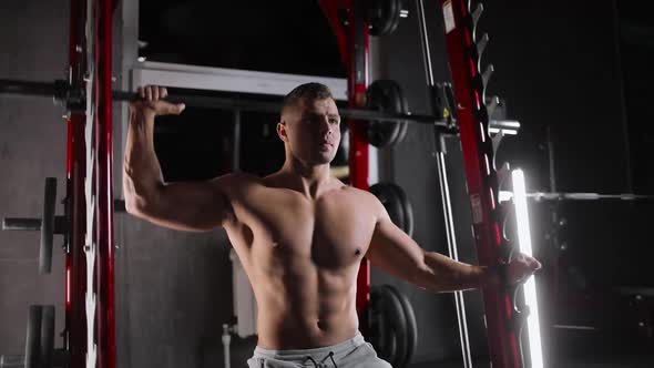 Portrait of an Athletic Young Man Exercising in the Gym Doing Strength Exercises Pushing a Barbell