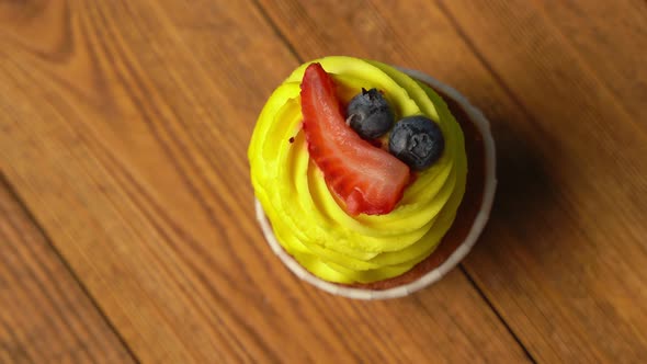 Top View of a Cupcake with Yellow Sweet Cream is Spinning on a Blue Background alt
