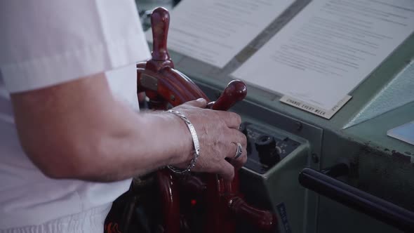 Captain Turns Wooden Steering Wheel on a Ship Sailing Through Sea. Driver Man Navigating Cruise. alt