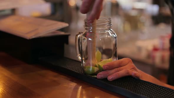Closeup of Bartender Making Mojito Cocktails with Lime Mint and Rum in Bar alt