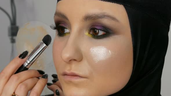 A Professional Artist Makes Makeup to a Beautiful Girl Model Feathering Powder Highlighter