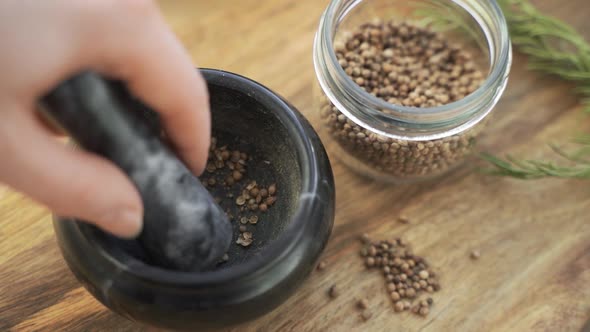 Woman's Hand Mixes and Crushes Coriander Seeds By Granite Mortar with Pestle in Slow Motion alt