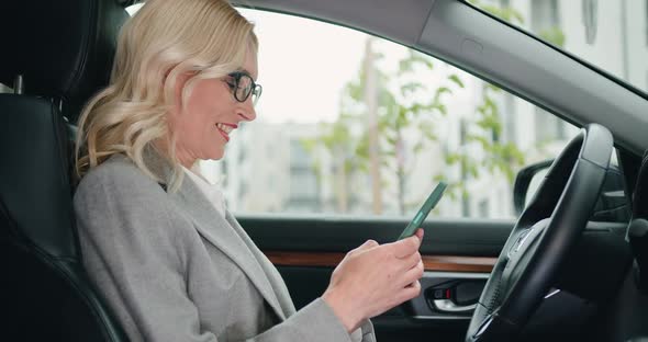 Woman Chatting or Browse Videos or Photos or Social Networks on Smartphone While Sitting in Car. alt