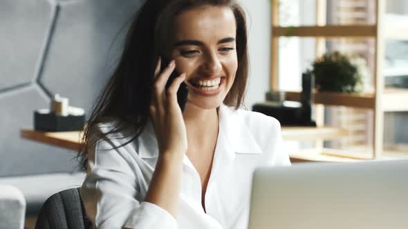 Smart and Charming Business Lady Talking on Phone While Sitting in Modern Cafe alt