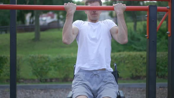 Motivated Focused Man in Wheelchair Doing Pull Ups in Slow Motion Outdoors alt