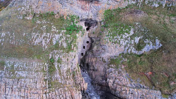 AERIAL: Close circle of man made cave in the side of cliff, Culver Hole, Port Eynon, Gower, 4k Drone alt