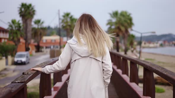 Blonde Woman Walking on Small Wooden Bridge in a Small City alt
