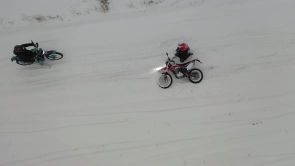 two guys riding motorcycles in the snow alt