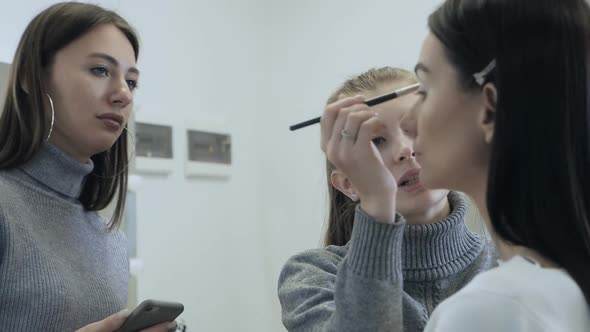Young Female Professional Makeup Artist Teaching Her Young Student to Become a Makeup Artist in a