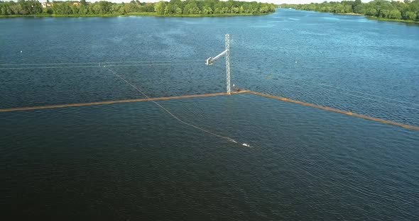 Aerial View of the Anchorage of the Cable Car Wake Park and an Athlete Cutting Through the Water on