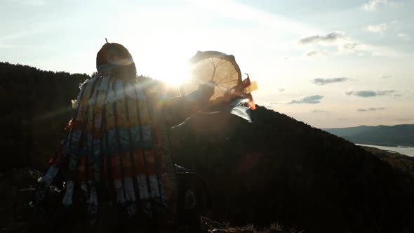 Slow Motion of the Silhouette of a Shaman with a Tambourine at Sunset.
