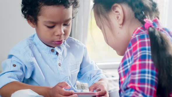 Little African Boy and Asian Girl Playing on Smartphone