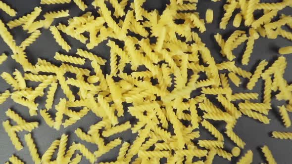 Slow Motion: Many Of Spiral Noodles Fall On A Black Table