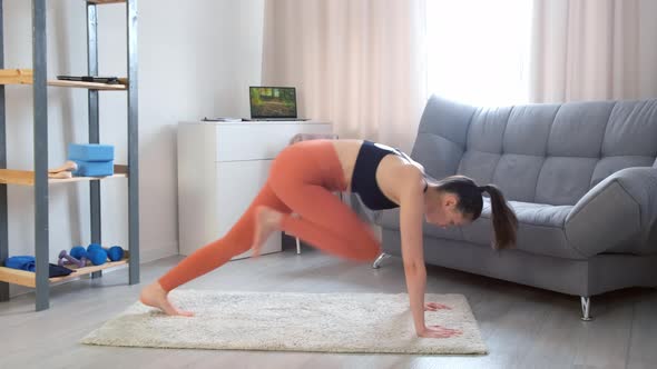 Young Woman Making Plank Flexing Legs Exercise in Dynamic at Home Side View