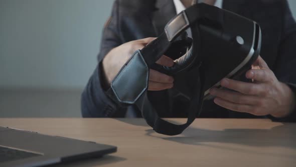 American Businessman Holding Vr Glasses in Hand Sitting at Table with Laptop in Office.
