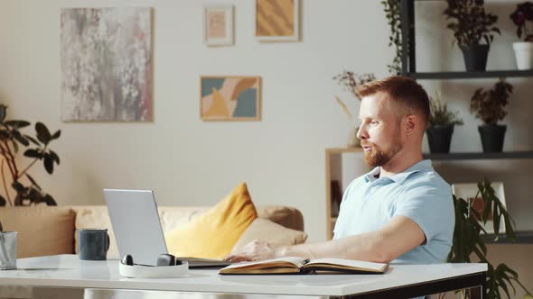 Cheerful Man Talking on Web Call on Laptop at Home alt