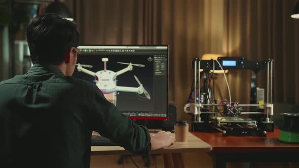 Over The Shoulder Asian Engineer Working On Personal Computer And 3D Printer alt