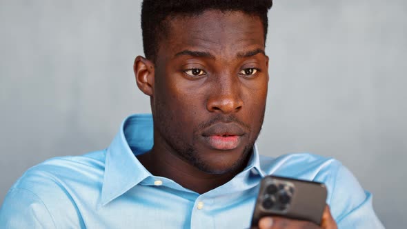 Young serious guy sending a message using a smartphone alt