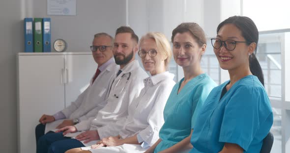 Medical Team Sitting in Row and Looking at Camera alt