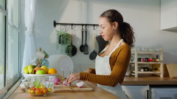 Latino attractive woman wear apron cook green salad in kitchen at home. alt