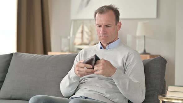 Worried Middle Aged Man Checking Empty Pocket for Money alt
