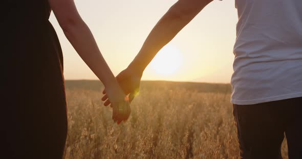 Couple In Love Holding Hands Against The Background Of The Sun. Close Up